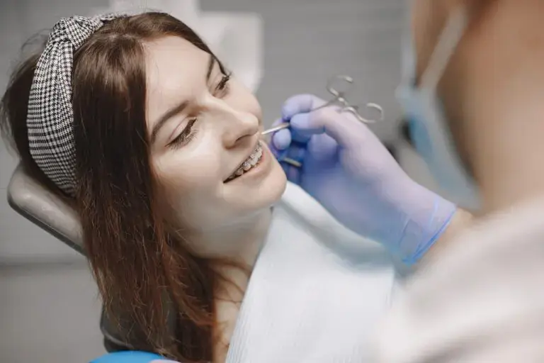 At Freelove Orthodontics in Sammamish or Kent, WA, a dentist in gloves examines a smiling woman’s teeth in a dental chair.