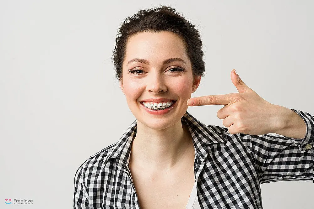 a woman pointing at her metal braces after considering aligners vs braces in kent and sammamish, wa