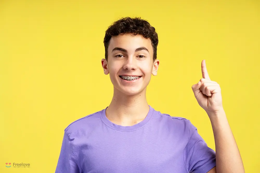Smiling teenage boy with braces raising one finger after understanding how long do braces take in Kent and Sammamish, WA